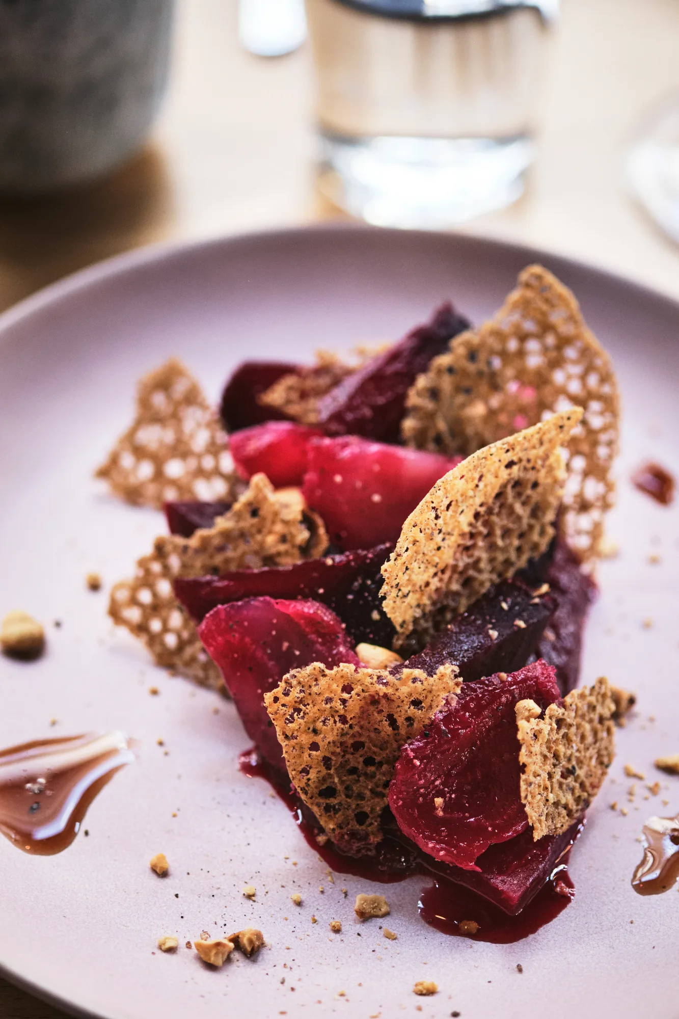Assiette bistronomique : betteraves rôties, tuiles ajourées et éclats de fruits secs sur céramique rose, au restaurant HABILE. Paris 10.