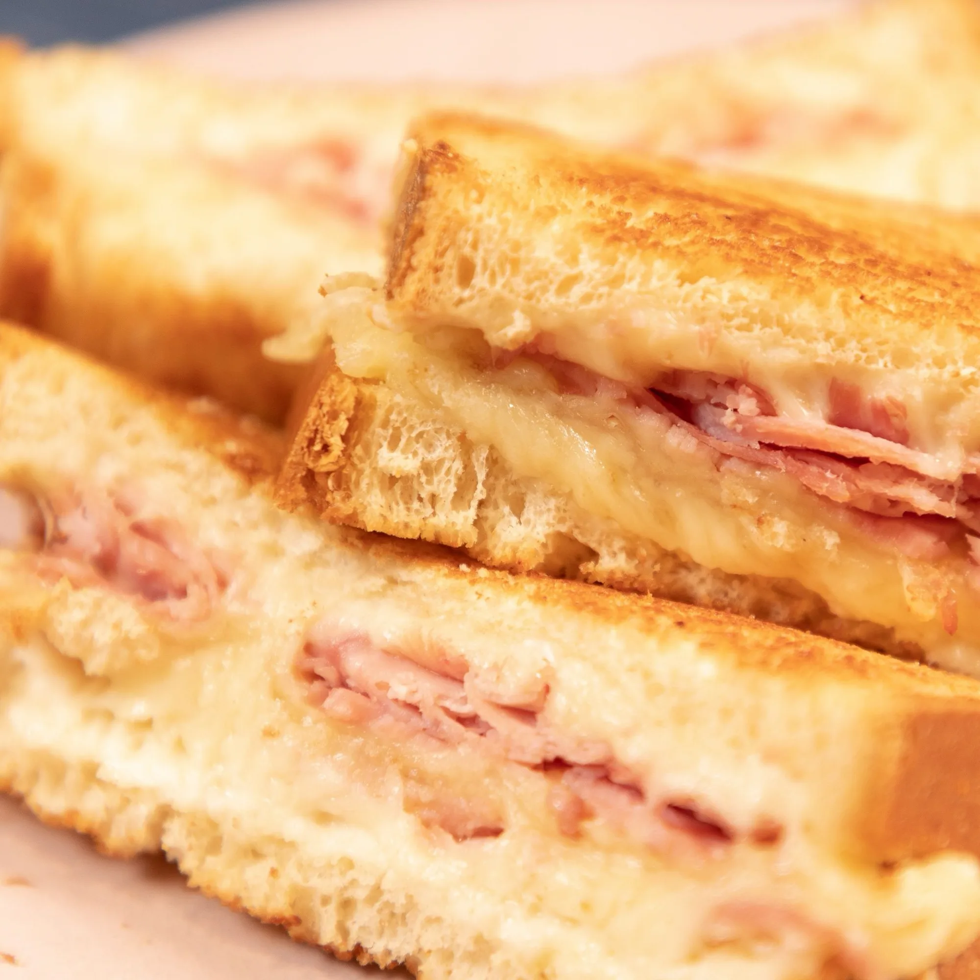 Croque-monsieur doré coupé en deux, fromage fondu et jambon généreux entre deux tranches de pain de mie grillé.