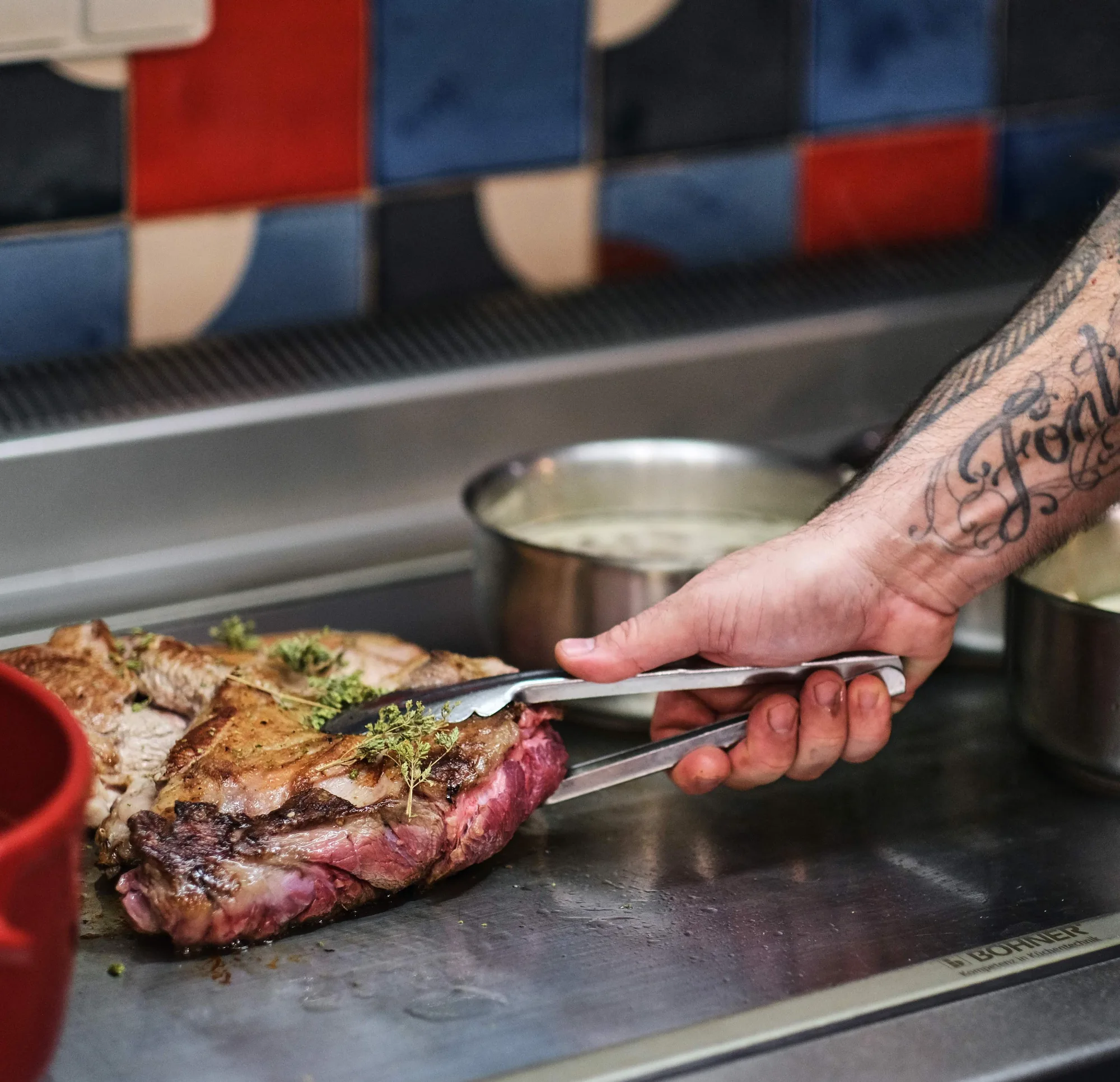 En cuisine chez HABILE., la main Eric Fontanini saisit une pièce de viande rôtie garnie de thym - restaurant HABILE - zoom
