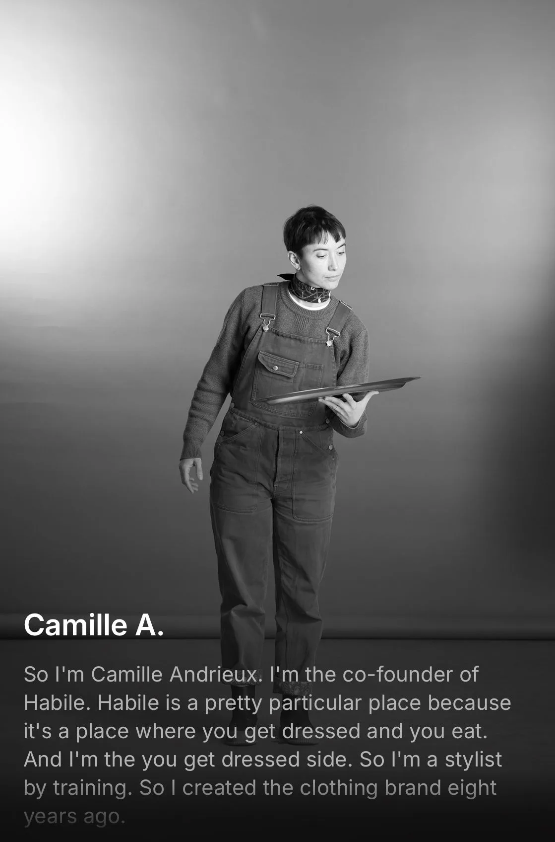 Une personne en salopette tient un plateau, fond neutre en noir et blanc — portrait lié à la Collection d'HABILE.